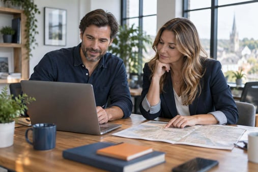 Two people reviewing a laptop and paper map in a bright office.