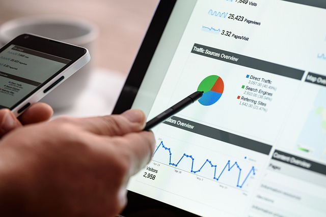 Person pointing to charts on a tablet while holding a smartphone.