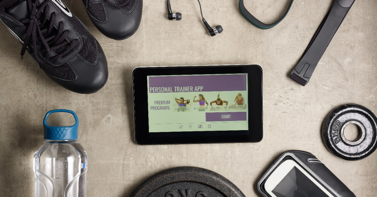 Personal trainer app displayed on a tablet beside exercise equipment