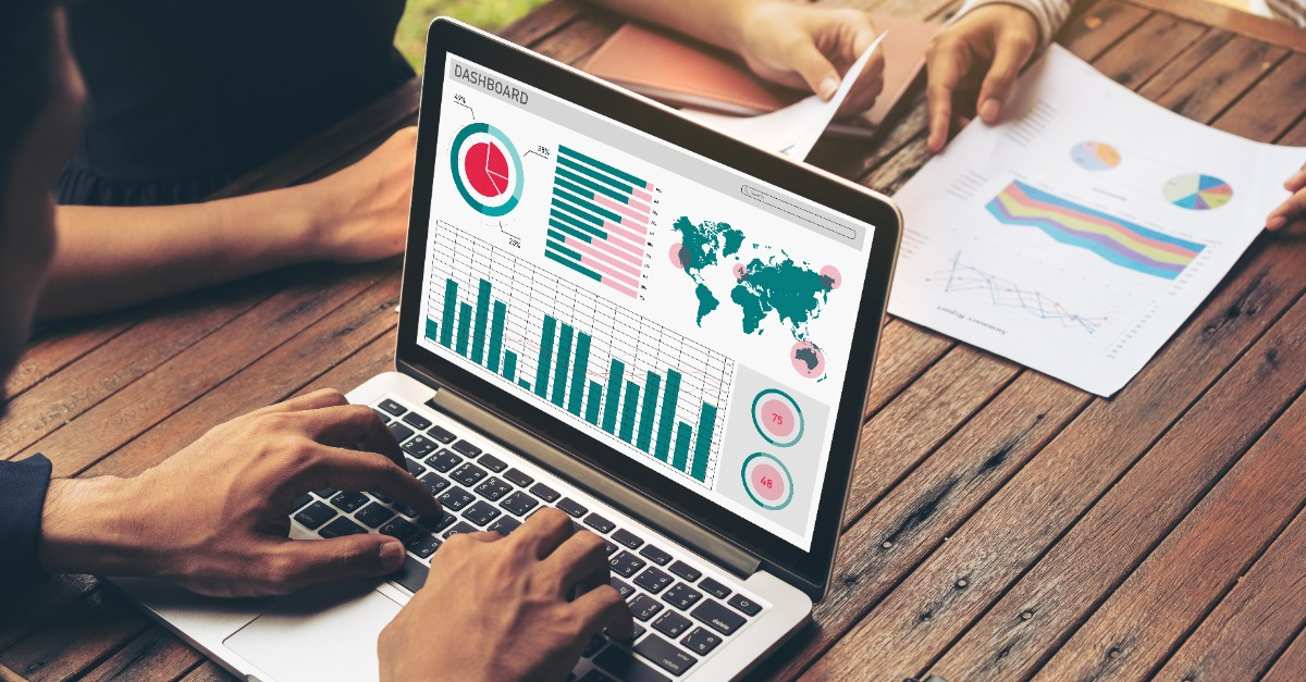Illustrative analytics dashboard on a laptop beside printed charts
