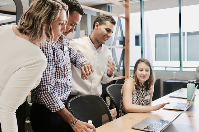 Four people gathered around laptops at an office table.