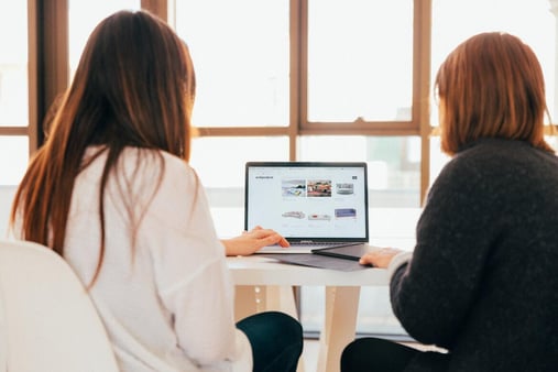 Two people viewing a website on a laptop at a table